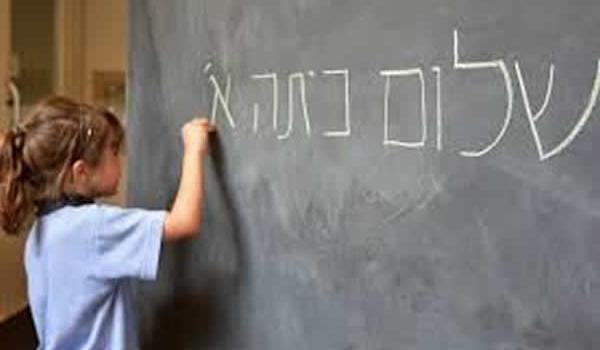 Student writing in Hebrew on a chalk board