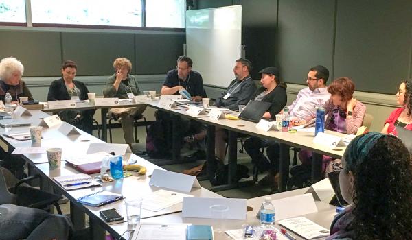 Group of CASJE affiliated professionals are seated around a large conference table in a meeting