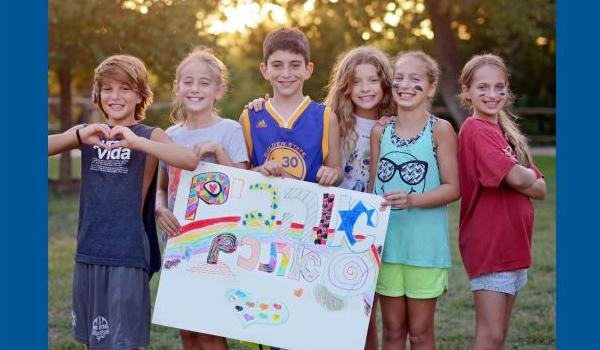 Children at Jewish summer camp holding a sign in Hebrew