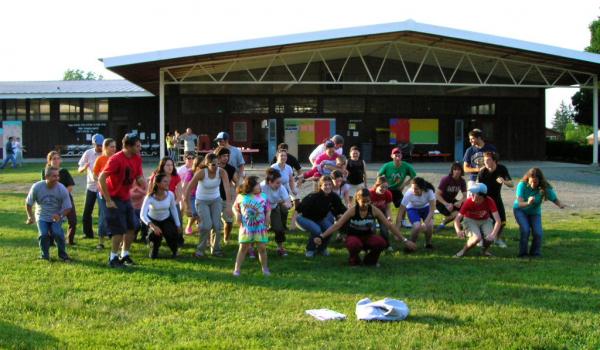 Campers dance in a large group outside of pavilion at summer camp