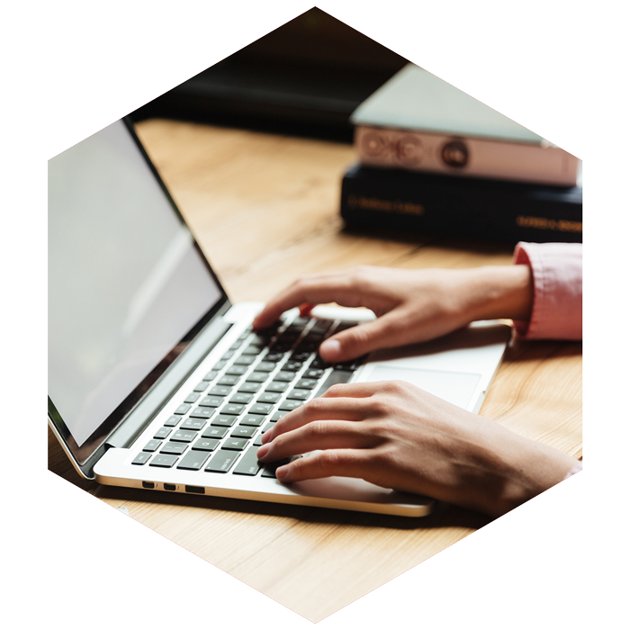 male hands typing on a laptop (image is hexagon shaped)