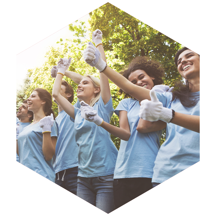 group of young females wearing matching tees and work gloves, excitedly cheering (image is hexagon shaped)