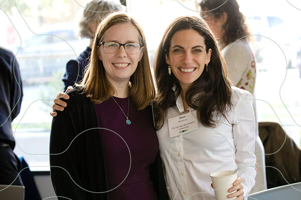 two young professionals pose together and smile for the camera at CASJE event