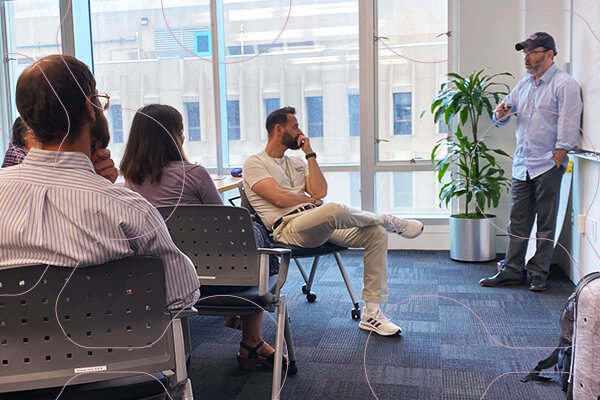 Fellowship mentor stands and speaks to small group of research fellows