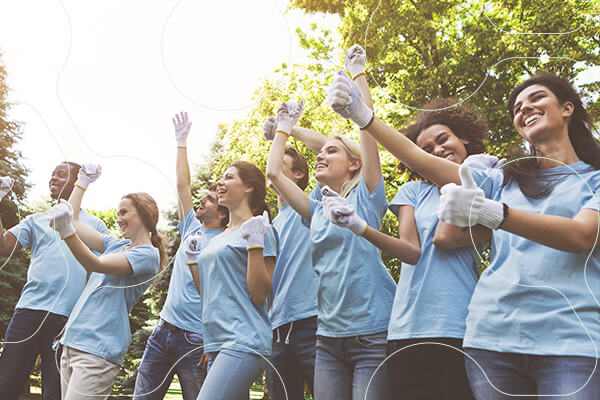 group of young females wearing matching tees and work gloves, excitedly cheering (image is hexagon shaped)