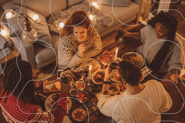 Three people at a dinner table, two candles and food on the table