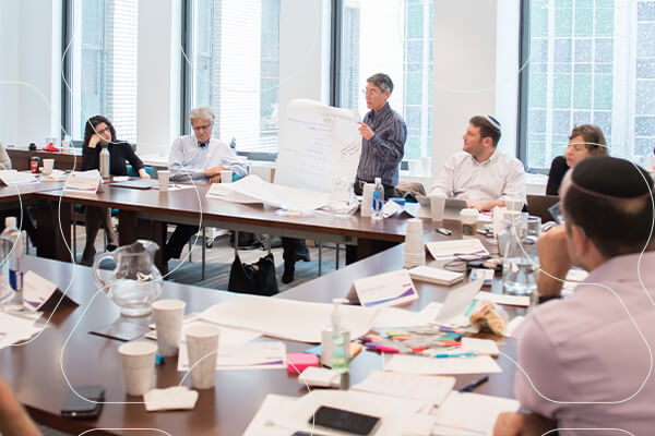 Group of CASJE affiliatesw around a conference table, one stands holding a large white sheet of paper for the group to see