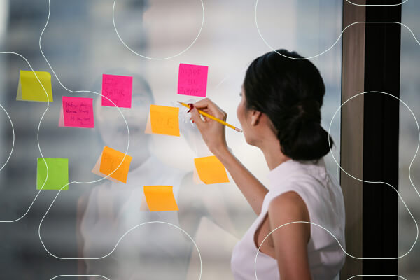 professional female writes on sticky notes posted on clear window