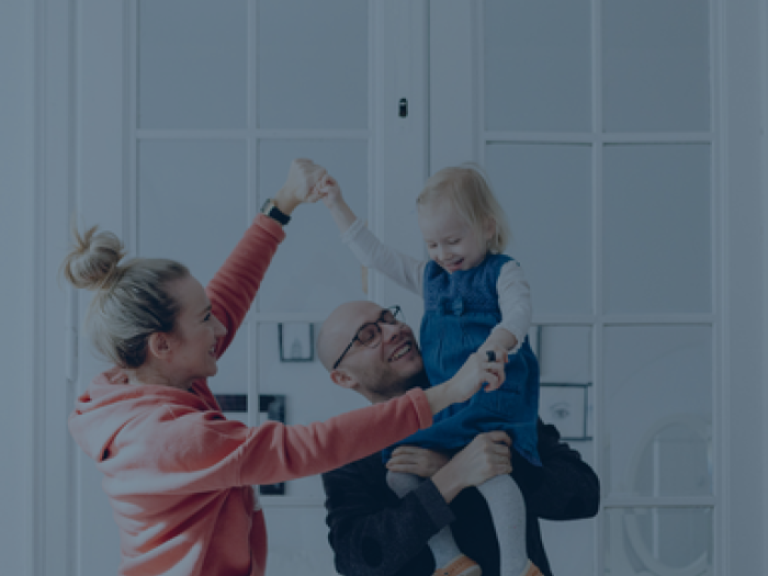 Family holding child in the air, blue background overlay