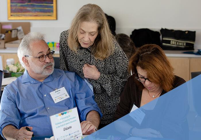 three professionals look at document on table at CASJE event