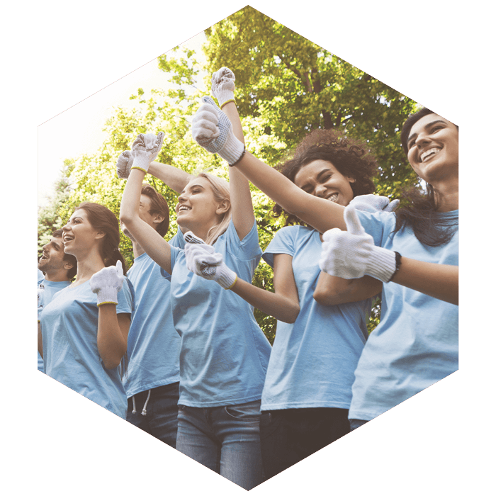 group of young females wearing matching tees and work gloves, excitedly cheering (image is hexagon shaped)
