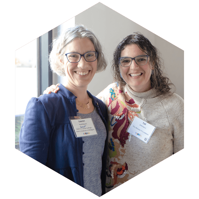 Lauren Applebaum and Tali Zelkowicz pose together and smile at camera at CASJE event (image is hexagon shaped)