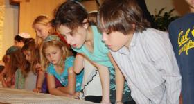 Young children look at a Torah